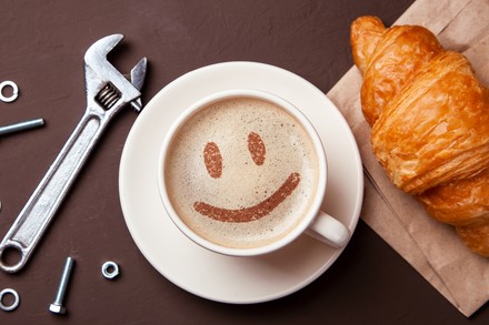 Eine Tasse Kaffee auf einem Tisch, neben der ein Schraubenschlüssel liegt