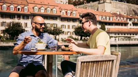 2 Männer sitzen am Ufer der Aare an einem Bistrotisch