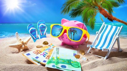 Ein Sparschwein mit Sonnenbrille und Gedscheinen an einem Palmenstrand