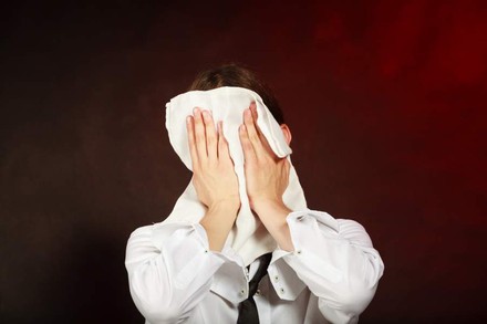 Kellner hält sich Serviette vor den Kopf