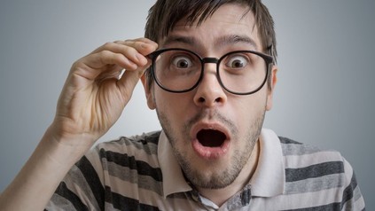 Nerd mit Brille sieht erstaunt in die Kamera