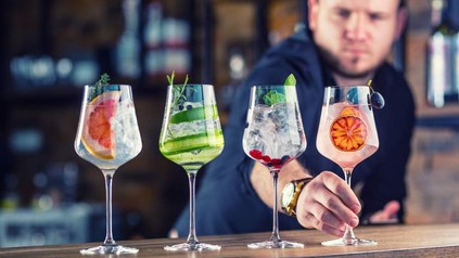 Ein Barkeeper, der vuier verschiedene Mixgetränke mit Gin vorbereitet