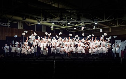 junge Köche werfen auf einer beleuchteten Bühne ihre Mützen in die Luft