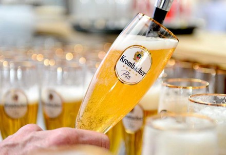 Eine Hand schenkt ein Krombacher Pils ein