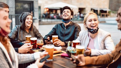 Gruppe junger Leute sitzt lachend bei einem Bier zusammen