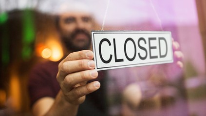 Mann hängt Geschlossen-Schild an Restauranttür
