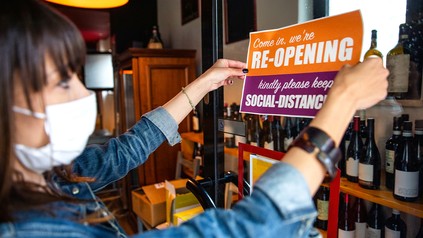 Frau hängt Re-Start-Schild an Restauanttür