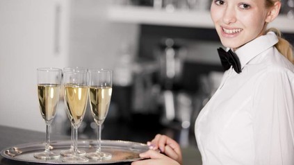 Eine junge Servicekraft beim Servieren von Sekt