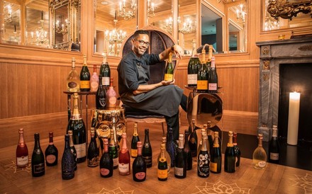 Luis Pereira Castillo sitzt zwischen Champagnerflaschen