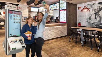 Tipos-Terminal bei einem KFC mit zwei jungen Kundinnen, die ein Selfie schießen