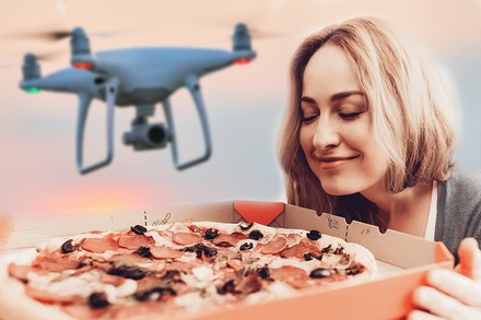 Eine Frau öffnet einen Pizzakarton, während über ihr eine Drohne schwebt