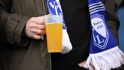 Mann hält Bierbecher in Stadion