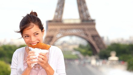 Kind isst Crepe vor dem Eiffelturm in Paris