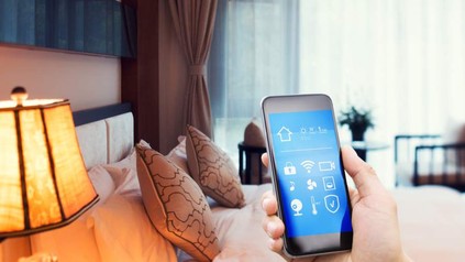 Eine Hand mit Smartphone in einem Hotelzimmer