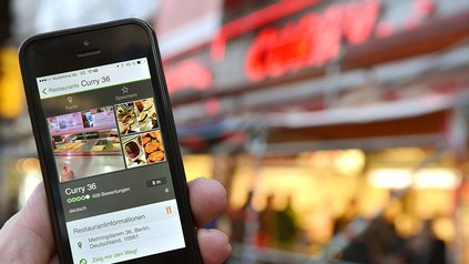 Ein Mann mit einem Handy vor einem Restaurant