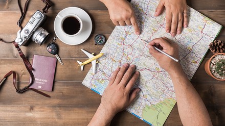 Zwei Menschen planen ihre Reiseroute über einer Landkarte