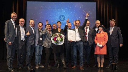 Eine Gruppe Gewinner auf der Bühne, die sich über Urkunden freuen