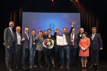 Eine Gruppe Gewinner auf der Bühne, die sich über Urkunden freuen