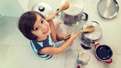 Kind schlägt mit Kochlöffeln auf Kochtöpfe