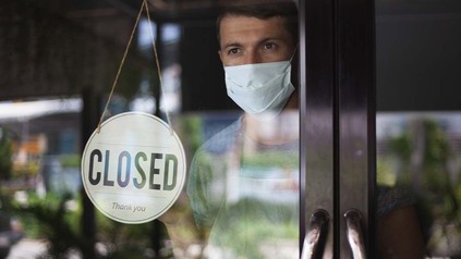 Gastronom steht an der Restauranttür hinter dem "Geschlossen"-Schild