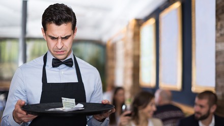 Ein Kellner begutachtet sein Trinkgeld