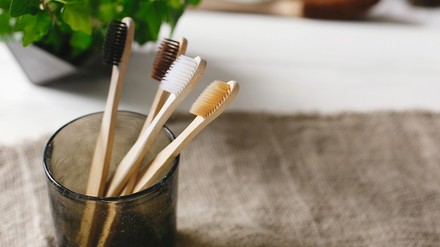 Nahaufnahme von vier Holz-Zahnbürsten in einem Zahnputzbecher im Badezimmer