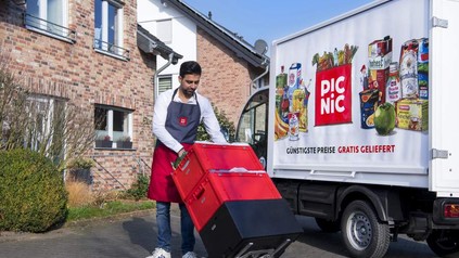 Ein Mitarbeiter von Picnic steht mit einigen Waren vor seinem Lieferwagen