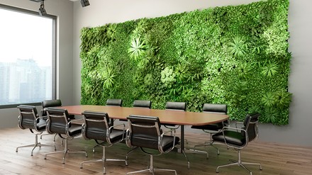 Tagungsraum mit großem Konferenztisch und Stühlen, im Hintergrund ein Wandbild mit echten grünen Pflanzen