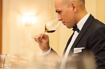 Eine Servicekraft riecht vor dem Servieren an einem Glas Wein