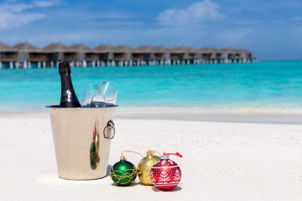 Ein karibischer Strand, auf dem ein Sekteimer und Christbaumkugeln stehen.