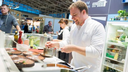 Ein Koch kocht an einemk Messestand für die Besucher