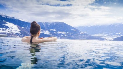 Frau in Pool blickt auf Berge