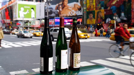 Drei Weinflaschen mit deutschem Wein vor einem Stadtpanorama in den USA