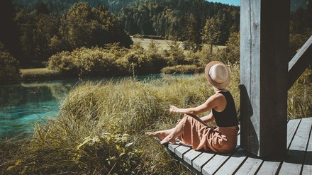 Der Tourismus-Sektor gilt aufgrund des Luftverkehrs nicht gerade als Vorzeigebeispiel für Nachhaltigkeit. Eigentlich sind die Emissionen durch Inlandstourismus von 2015 bis 2019 jedoch um 9,9 Prozent gesunken. (Foto: © nataliaderiabina – stock.adobe.com)
Junge Frau sitzt auf der Veranda einer Hütte in der unberührten Natur