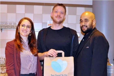 Philip Ibrahim, Hoteldirektor des Mercure Hotel Berlin City, und Franziska Lienert von „Too Good To Go“ freuen sich über die 100.000 gerettete Mahlzeit in Berlin. Kunde Robert Reinicke hält sie stolz in Händen.