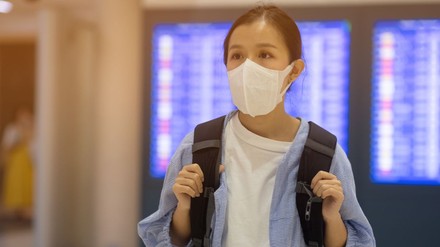asiatische Touristin mit Mundschutz in einer Abflughalle