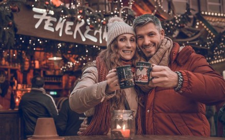 Paar auf Weihnachtsmarkt stößt mit Glühwein an