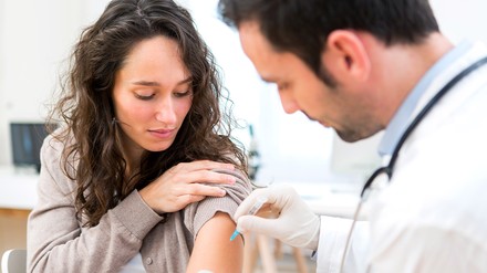 Junge Frau wird vom Arzt geimpft