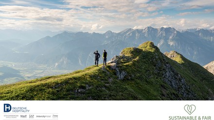 Blick auf einen Berggipfel auf dem zwei Wanderer stehen