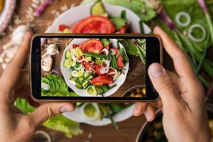Nicht alle deutschen Kettenrestaurants sind auf Veggies eingestellt. Doch Experten sehen in der veganen Ausweitung des Sortiments ein großes Zukunftspotenzial. (© Viktor Kochetkov/Fotolia)
Eine Frau macht ein Handyfoto von einem veganen Essen