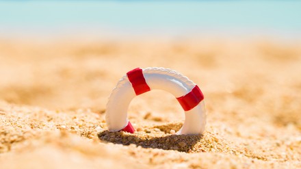 Kleiner Rettungsring als Symbol im Sand