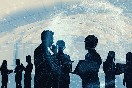 Die Silhouetten einiger Besucher auf einem Messegelände