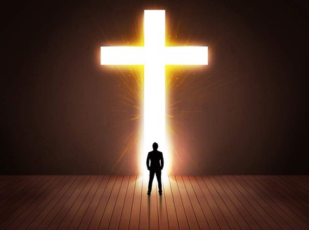 Mann steht vor leuchtendem Kreuz