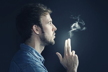 Mann hält Finger wie Pistole. Aus den Fingern tritt Rauch aus