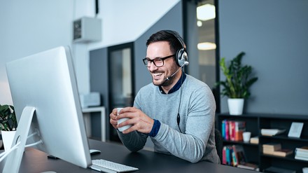 Mann sitzt vor dem PC mit Headset