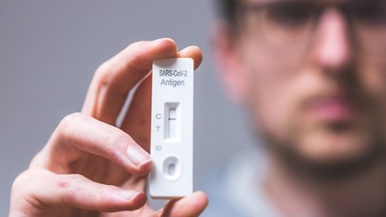 Mann hält negativen Schnelltest in die Kamera