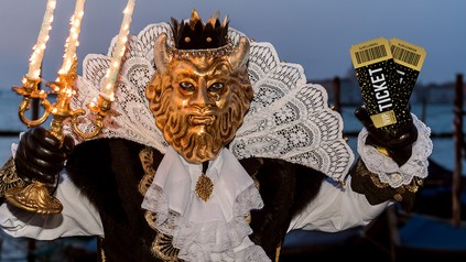 Ein Mann im venezianischen Karnevalskostüm mit Eintrittstickets in der Hand