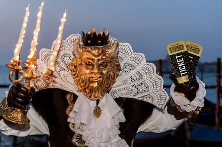 Ein Mann im venezianischen Karnevalskostüm mit Eintrittstickets in der Hand