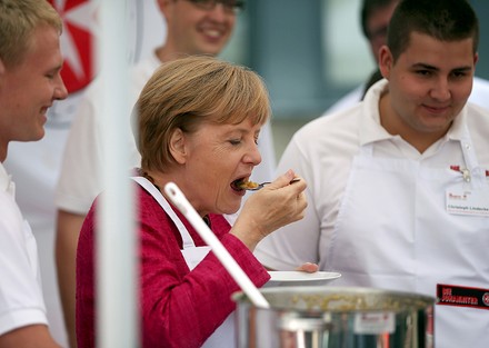 Kanzlerin Angela Merkel mit mehreren Köchen in einer Küche
