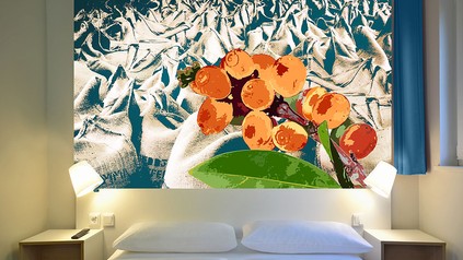 Ein Hotelzimmerbett mit einem modernen Gemälde an der Wand dahinter